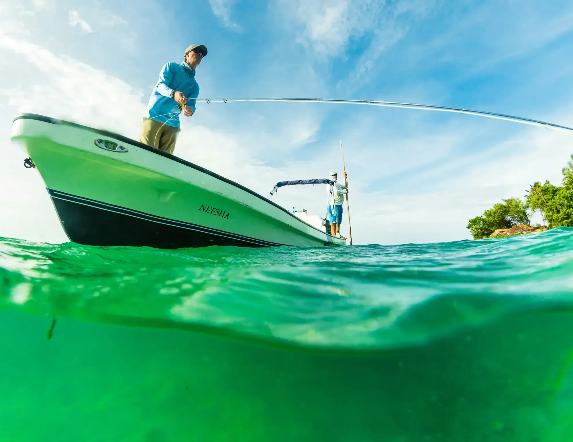 Empty saltwater flat at dawn in Belize, a single fly fishing skiff being poled in calm conditions