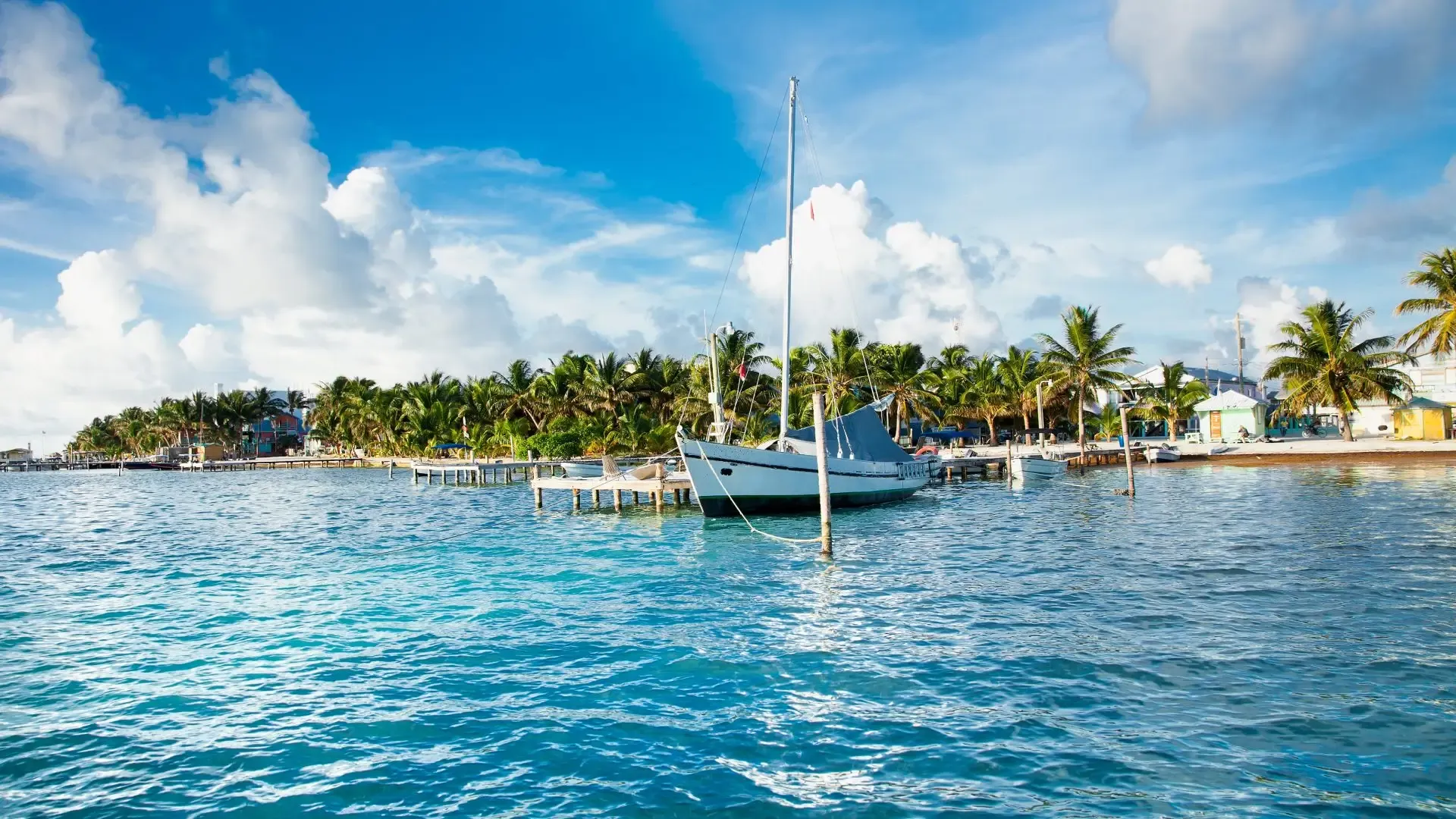 Colorful wooden fishing boats moored in the calm lagoon at Caye Caulker, Belize — laid-back Caribbean island fishing base
