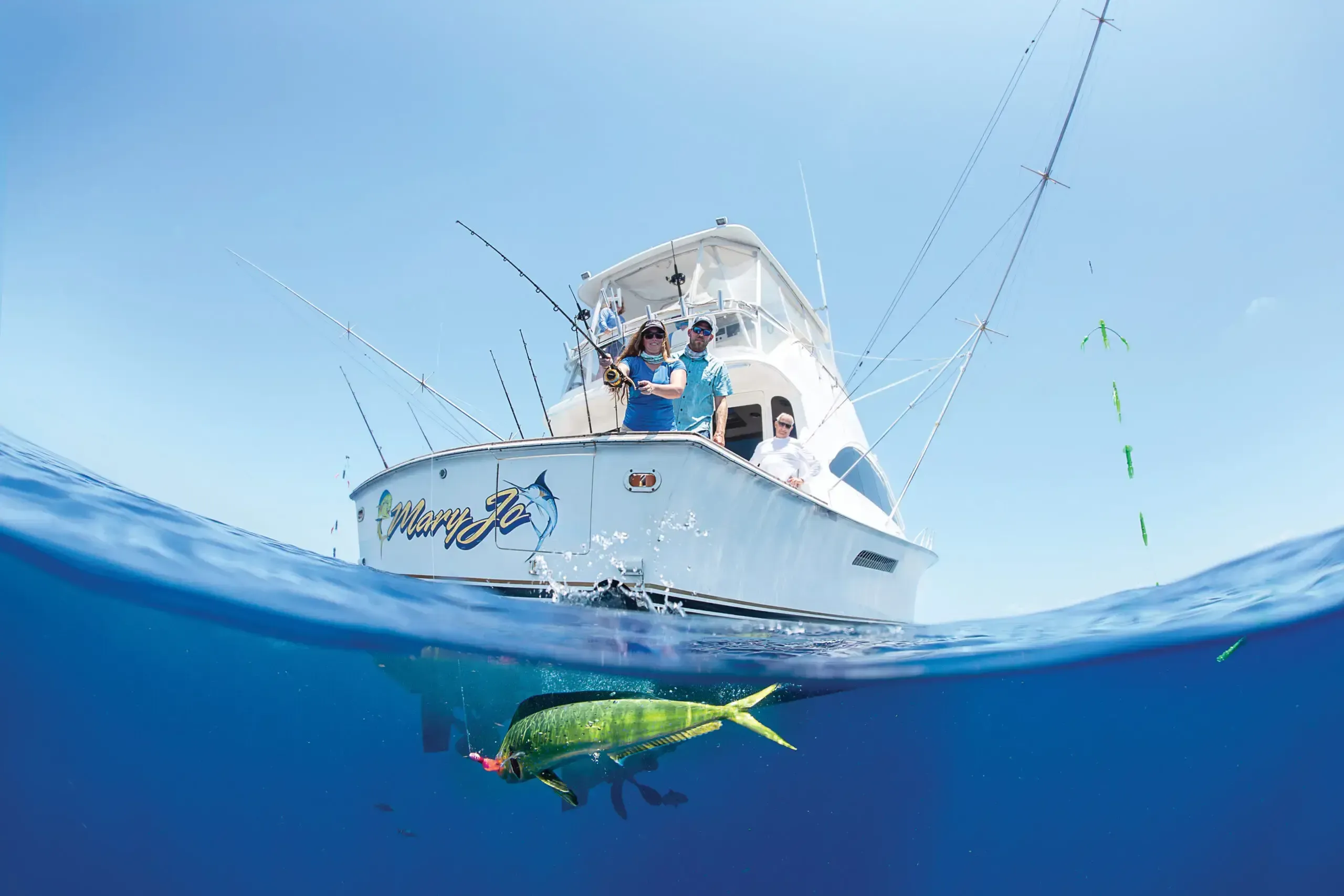 Angler fighting a large sailfish alongside a sportfishing charter boat in the offshore waters of Placencia, Belize