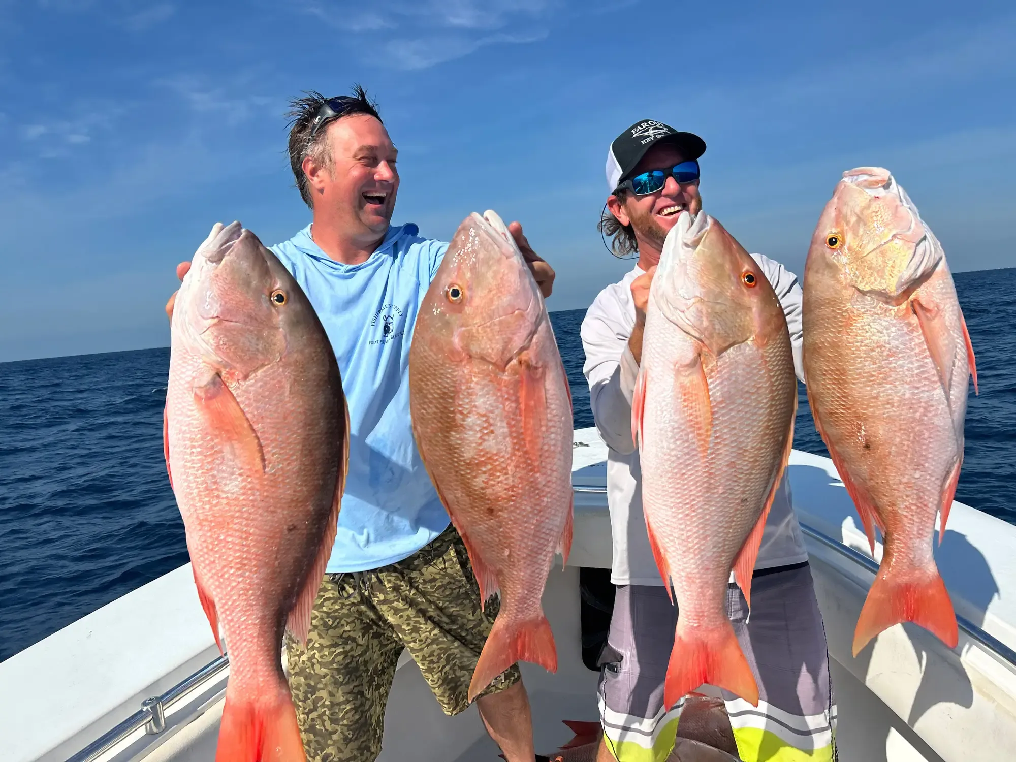 Fresh mutton snapper held at the side of a small fishing skiff near Caye Caulker, Belize — reef fishing in clear turquoise water