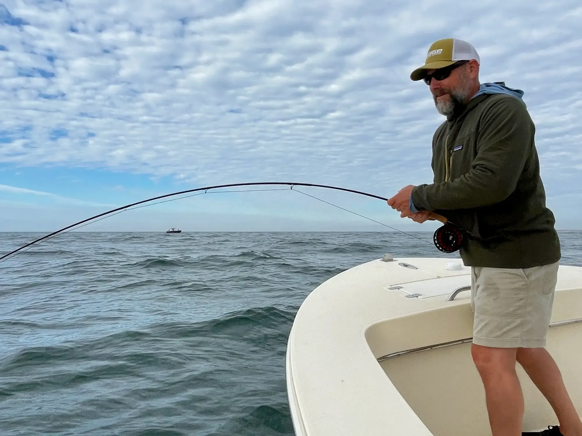 Ryan Cole guiding on the flats of Ambergris Caye, Belize — fly rod raised at dawn, permit water stretching to the horizon